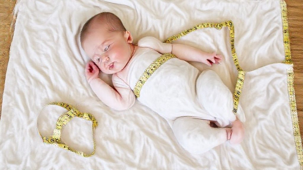 A measuring tape laid out next to a folded baby blanket, indicating size.